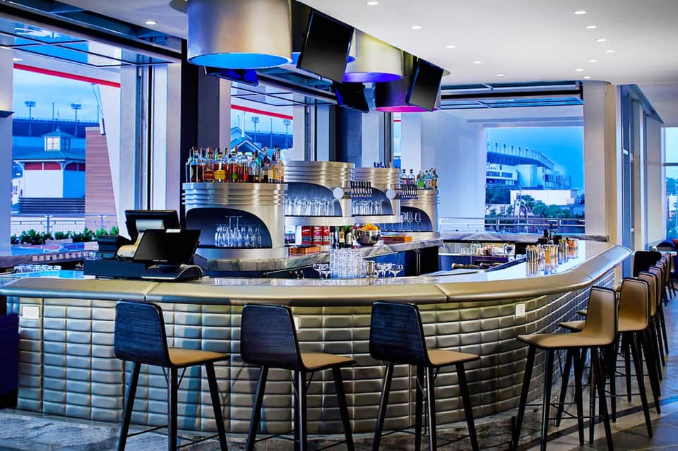 Modern bar with curved counter, blue uplighting, high seating, and water view windows