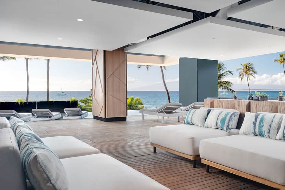 Modern beachfront lounge with white seating, ocean views, palm trees, and contemporary design