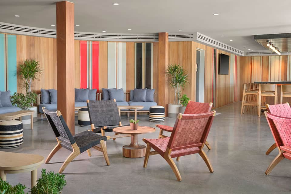 Modern lounge area with wooden dividers, colorful striped walls, mid-century chairs, and potted plants