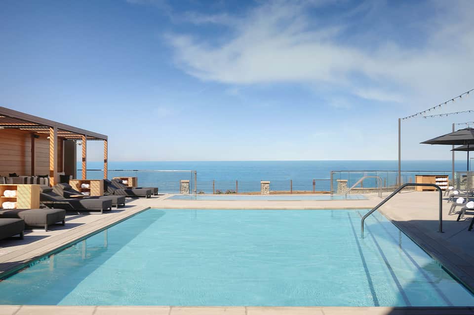 Luxury oceanfront pool with cabanas, lounge chairs, pristine blue water and sea horizon
