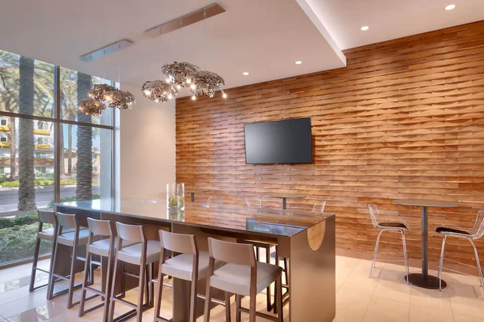 Contemporary lounge area with wooden wall, hanging pendant lights, and high-top bar seating