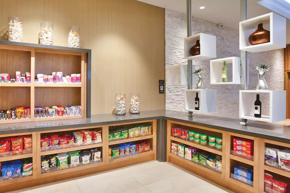 Resort convenience store with wooden shelving displaying snacks, beverages, and travel amenities