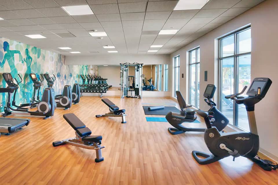 Spacious fitness center with cardio equipment, weight machines, motivational wall art, and large windows