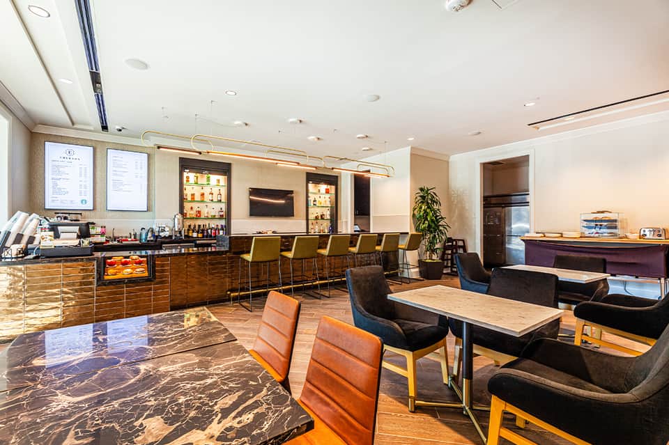 Contemporary hotel bar and lounge with bronze chairs, bar seating, and warm lighting