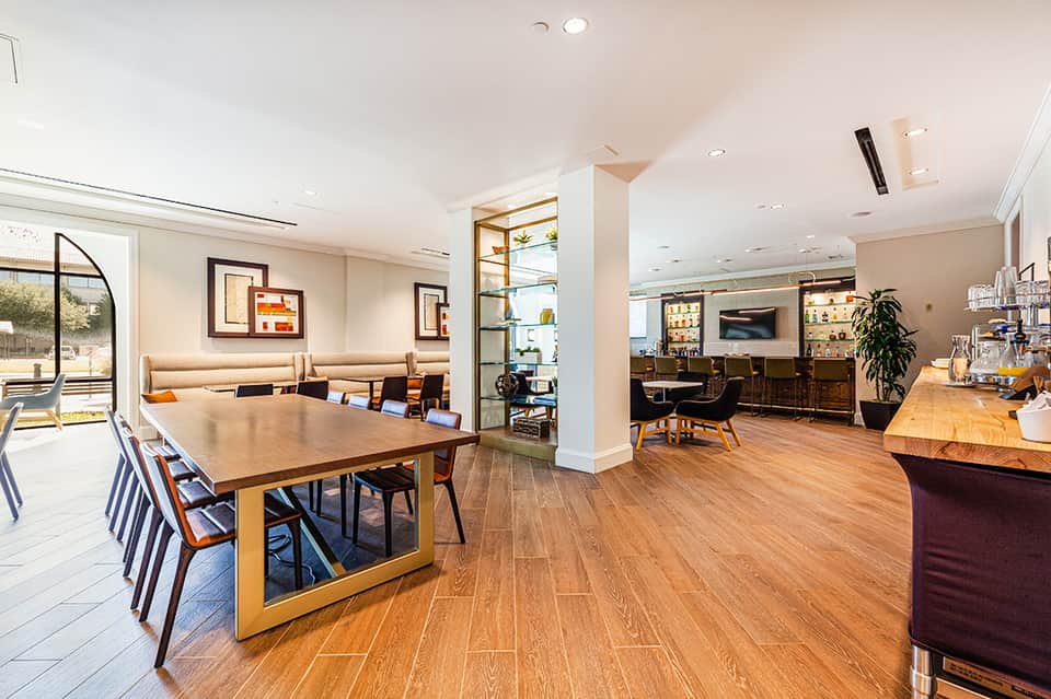 Modern hotel common area with wooden dining table, lounge seating, and contemporary furnishings