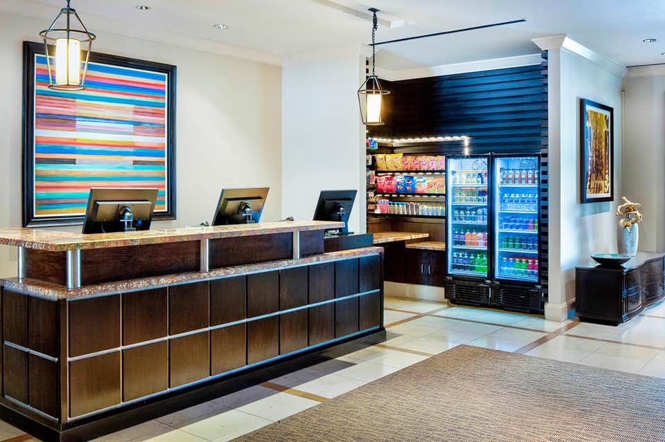 Modern hotel lobby with colorful art, reception desk, and beverage station