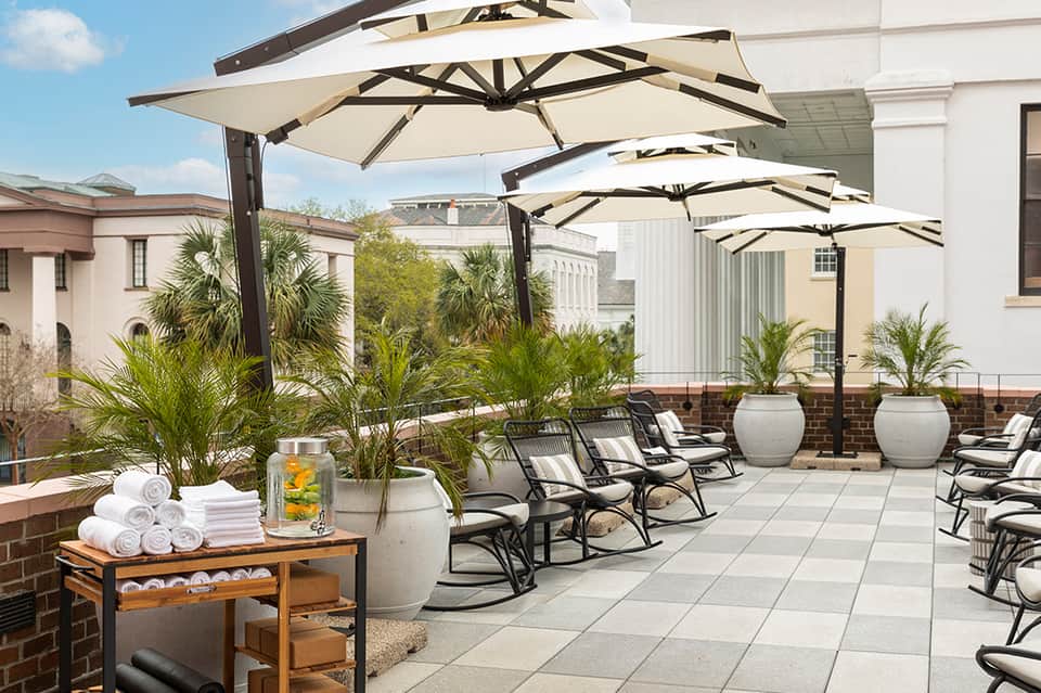 Elegant rooftop terrace with cantilever umbrellas, lounge chairs, and palm trees