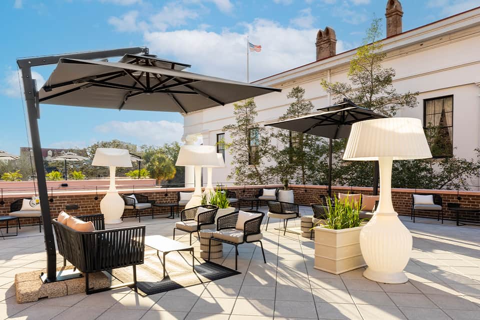 Modern rooftop terrace with cantilever umbrellas, lounge seating, and illuminated planters