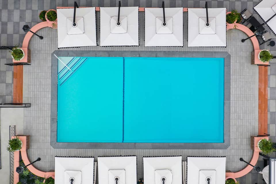 Aerial view of bright turquoise swimming pool surrounded by white lounge chairs and planters