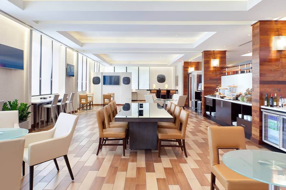 Contemporary lounge area with dining table, tan leather chairs, and full bar with wood accents