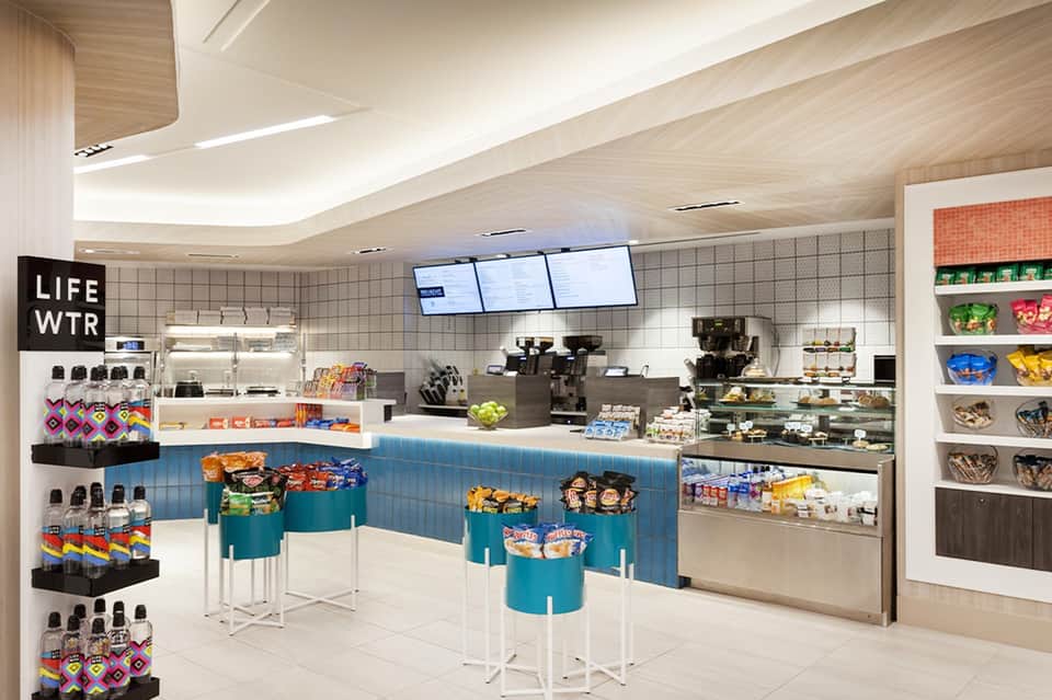 Modern hotel café with white pendant lights, wood counter, menu boards, and bright seating