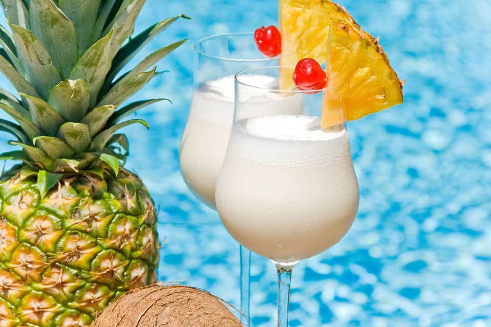 Tropical cocktail with pineapple garnish and cherry by swimming pool