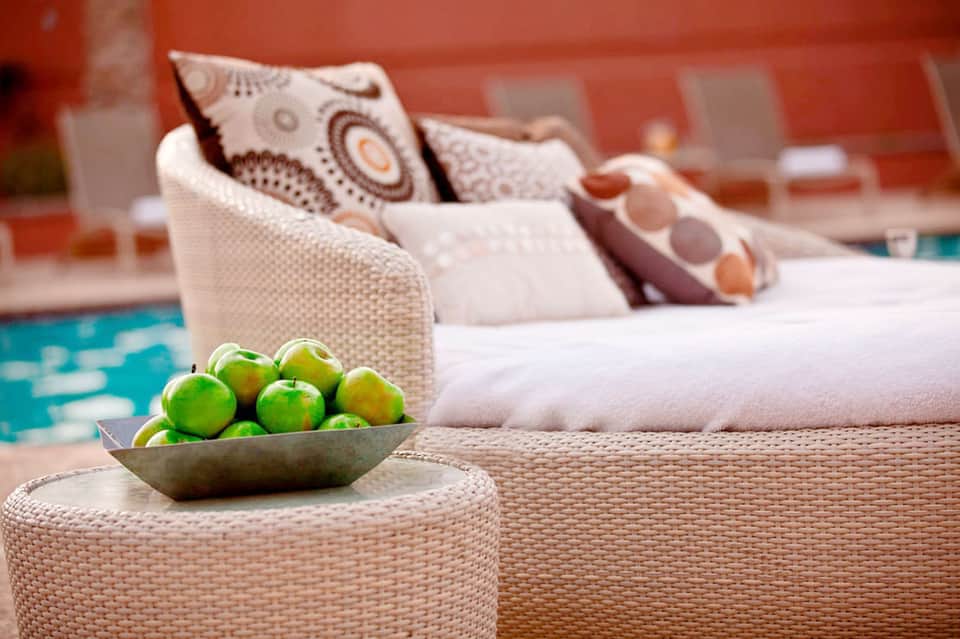 Poolside seating area with woven furniture, decorative apples, and tropical ambiance