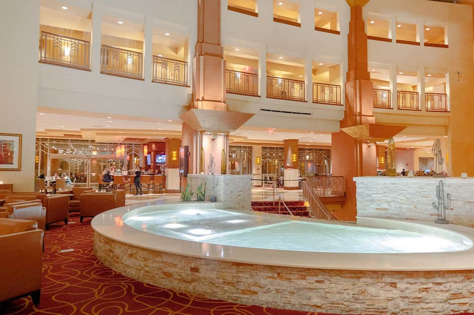 Grand resort lobby with tall ceilings, columns, and large circular water features with indoor seating