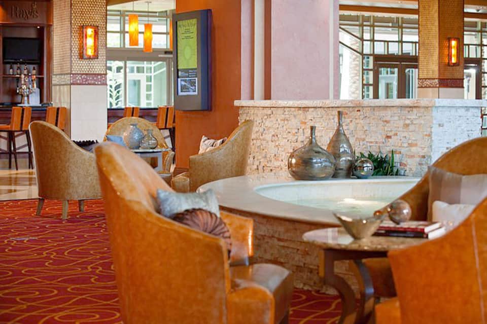 Hotel lounge with orange leather chairs, stone fireplace, and contemporary décor