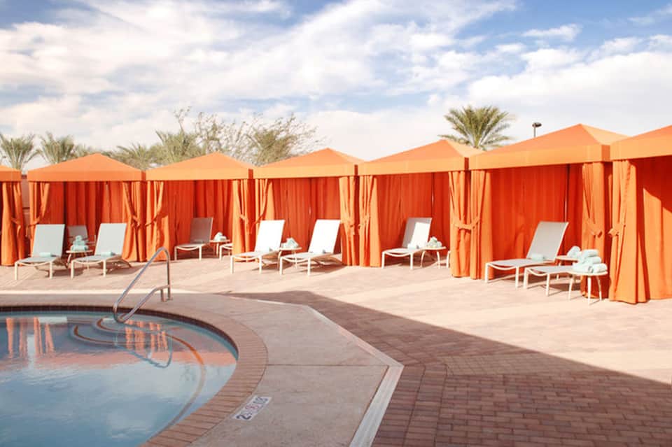 Pool area with orange cabanas and lounge chairs in a desert resort setting