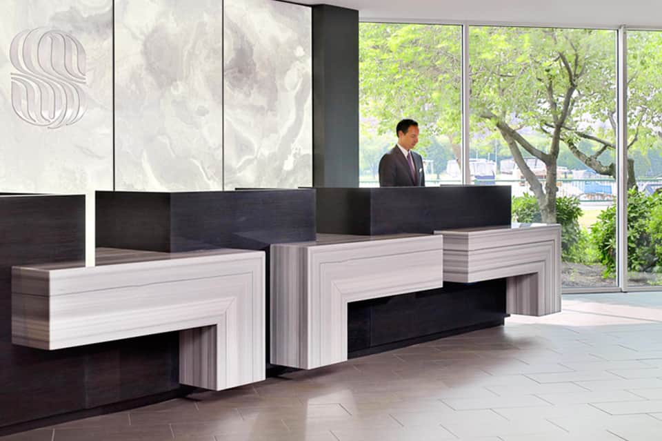 Modern hotel lobby with contemporary reception desk, floor-to-wall windows, and waterfront views