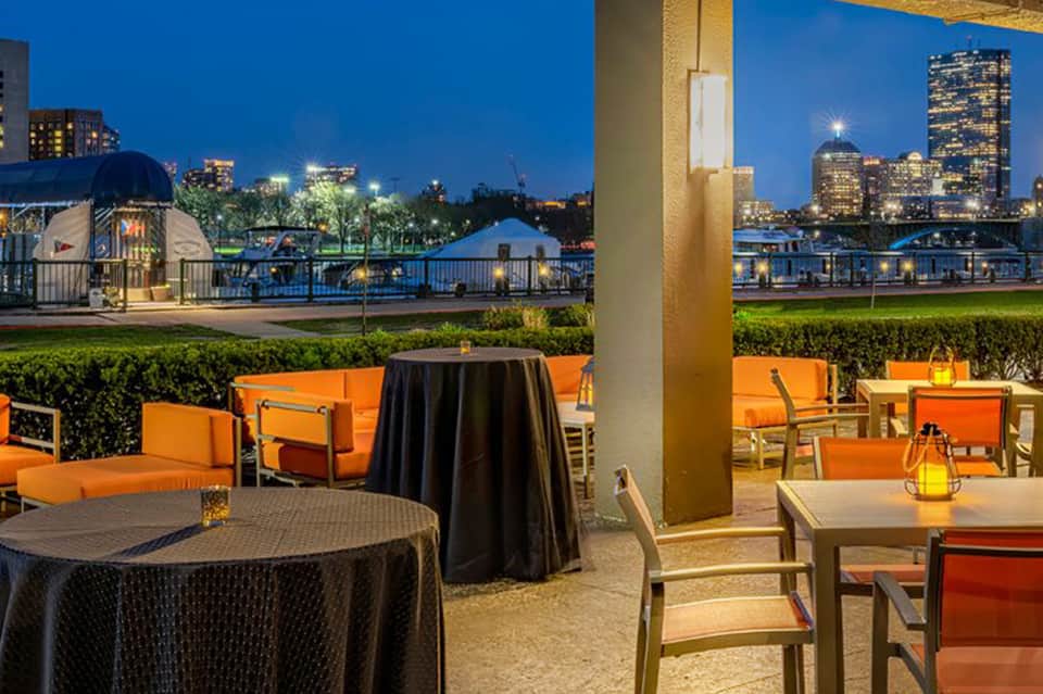 Evening outdoor terrace with orange seating, city skyline views, and illuminated waterfront
