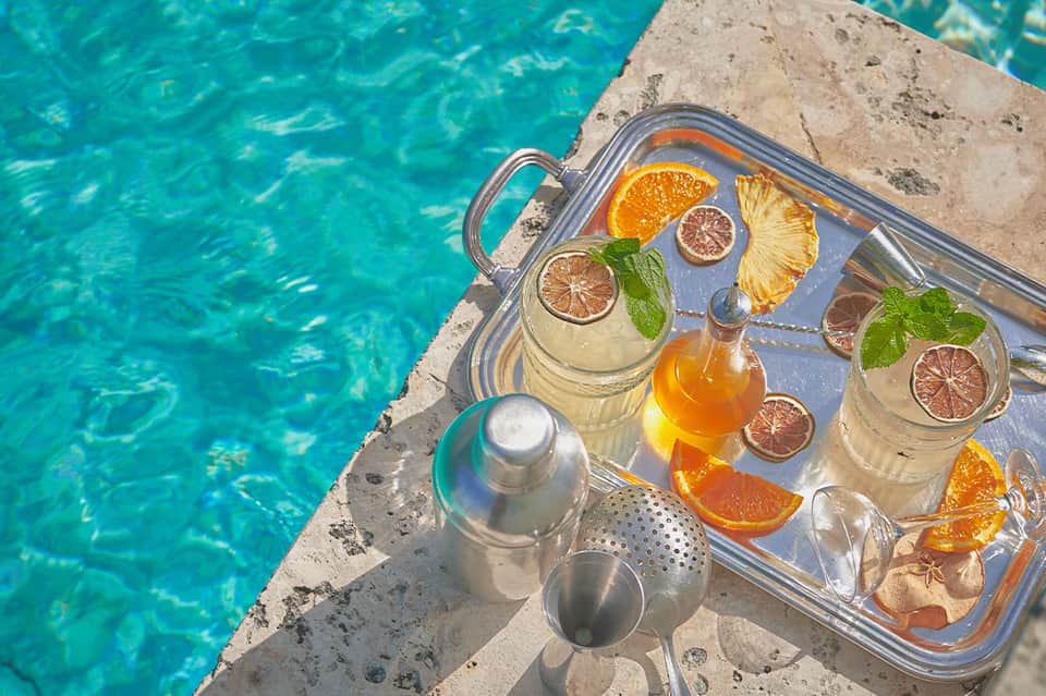 Refreshing beverage service on pool edge with citrus garnishes and sparkling water