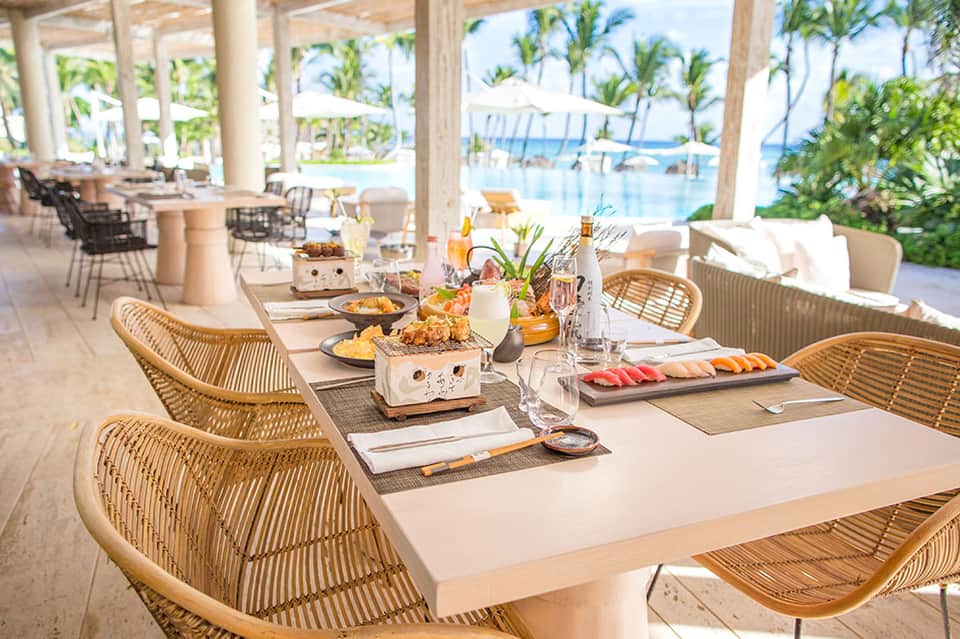 Elegant beachfront dining setup with rattan chairs and ocean views