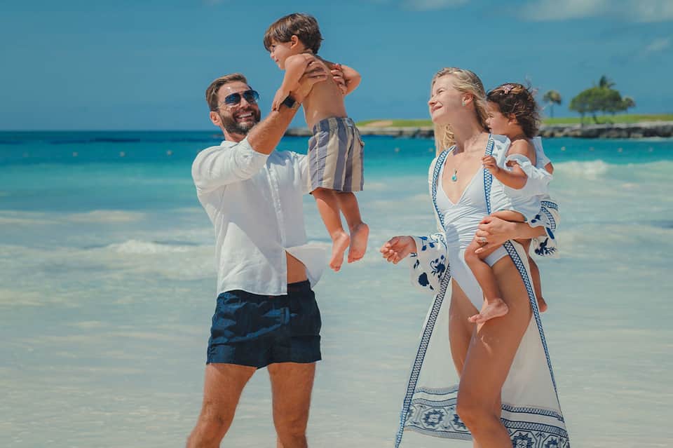 Family playing in shallow turquoise ocean water at tropical beach