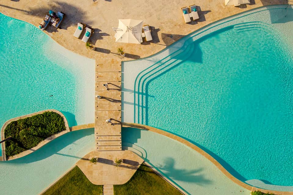 Aerial view of beachfront infinity pool with lounge chairs and turquoise water