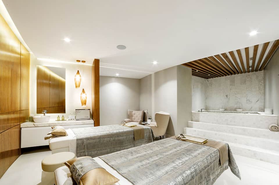 Spa treatment room with two beds, marble accents, and ambient lighting