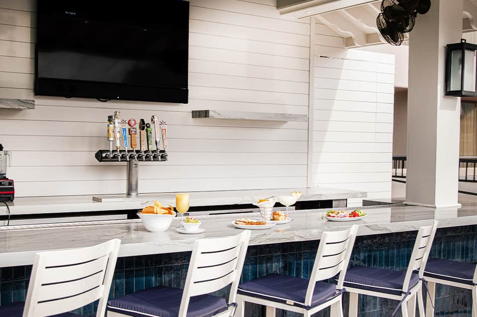 Modern lounge bar with white and navy seating, marble countertop, and craft beer tap system