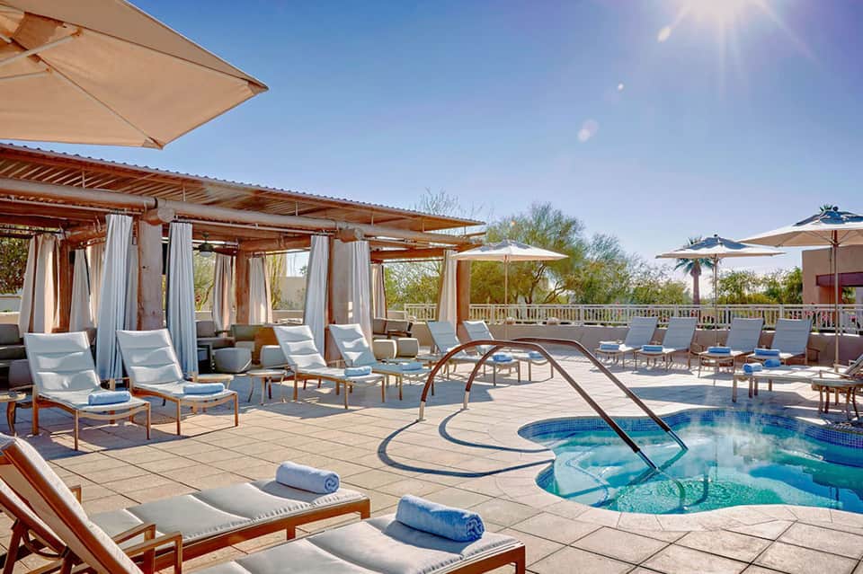 Luxury resort pool deck with cabanas, umbrellas, lounge chairs, and spa features