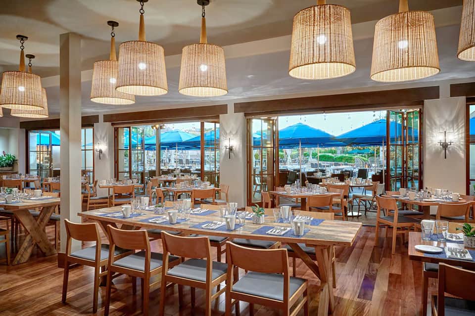Fine dining restaurant with wooden tables, pendant lights, and panoramic mountain views
