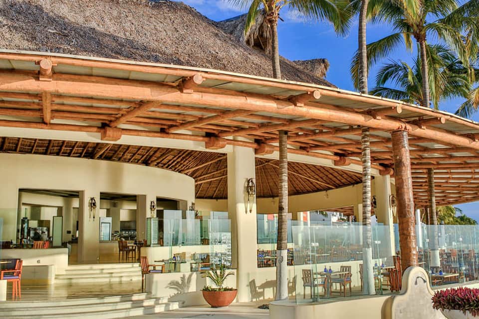 Beachfront restaurant with thatched roof, wooden beam architecture, and ocean views