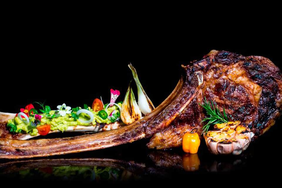 Grilled steak with decorative salad plated on slate against black background