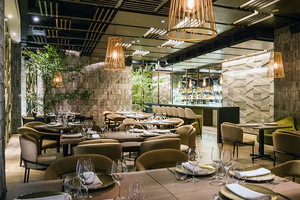 Upscale restaurant interior with elegant seating, pendant lighting, and green plants