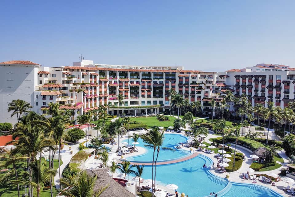 Resort aerial view showing curved pool, palm-lined grounds, and colorful building architecture