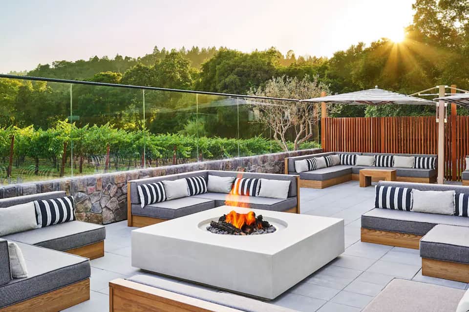Vineyard terrace with modern seating, striped pillows, fire pit, and mountain landscape