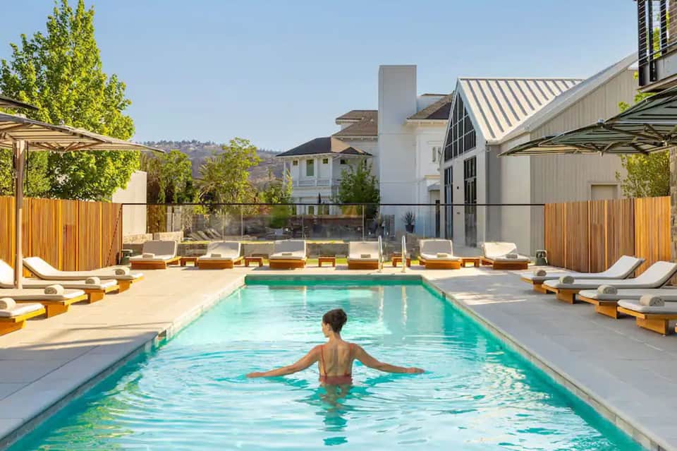 Resort swimming pool with lounge chairs and modern architectural building.