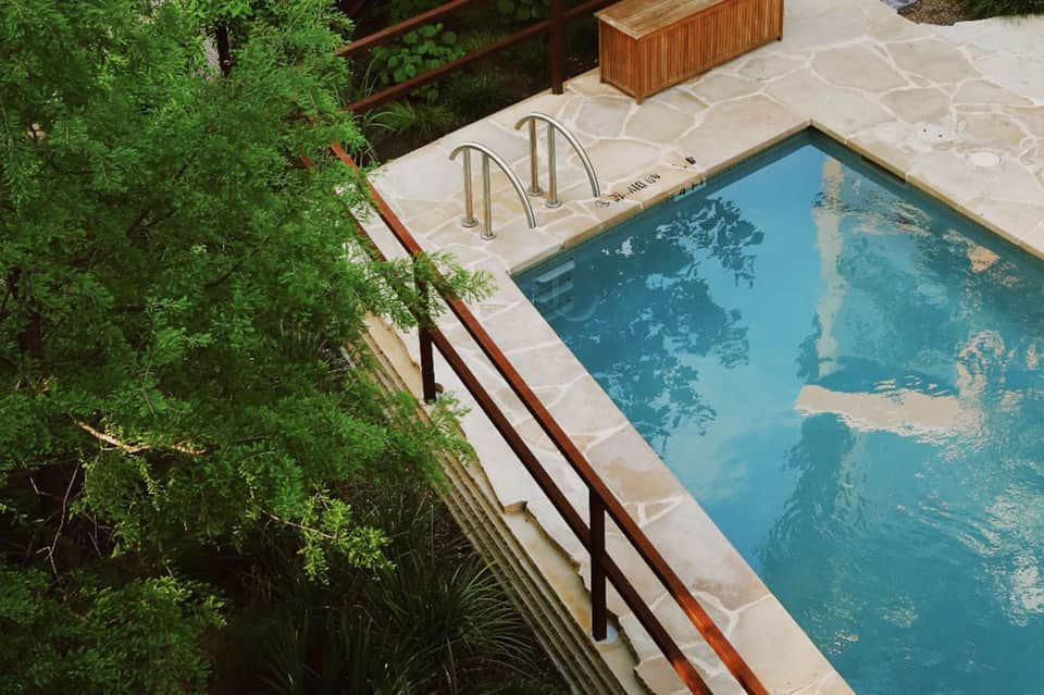 Overhead view of rectangular pool with steel railings and surrounding green landscaping and vegetation