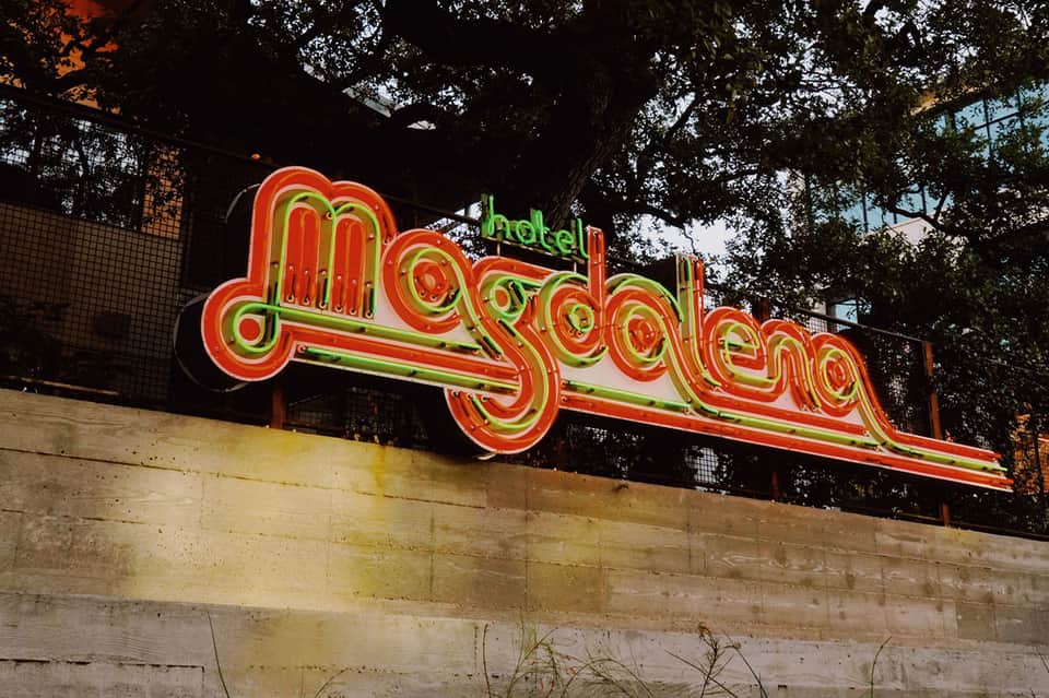 Vintage neon sign reading 'Hotel Myrtle Golden' in red and yellow lights under tree branches