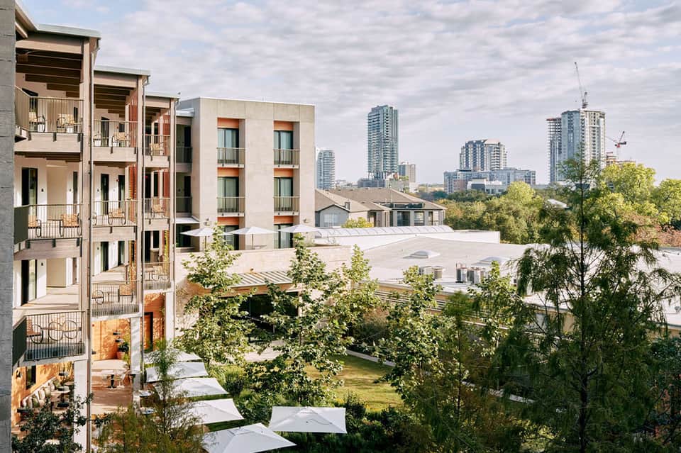 Modern residential courtyard with multi-story apartment buildings, green spaces, and city skyline