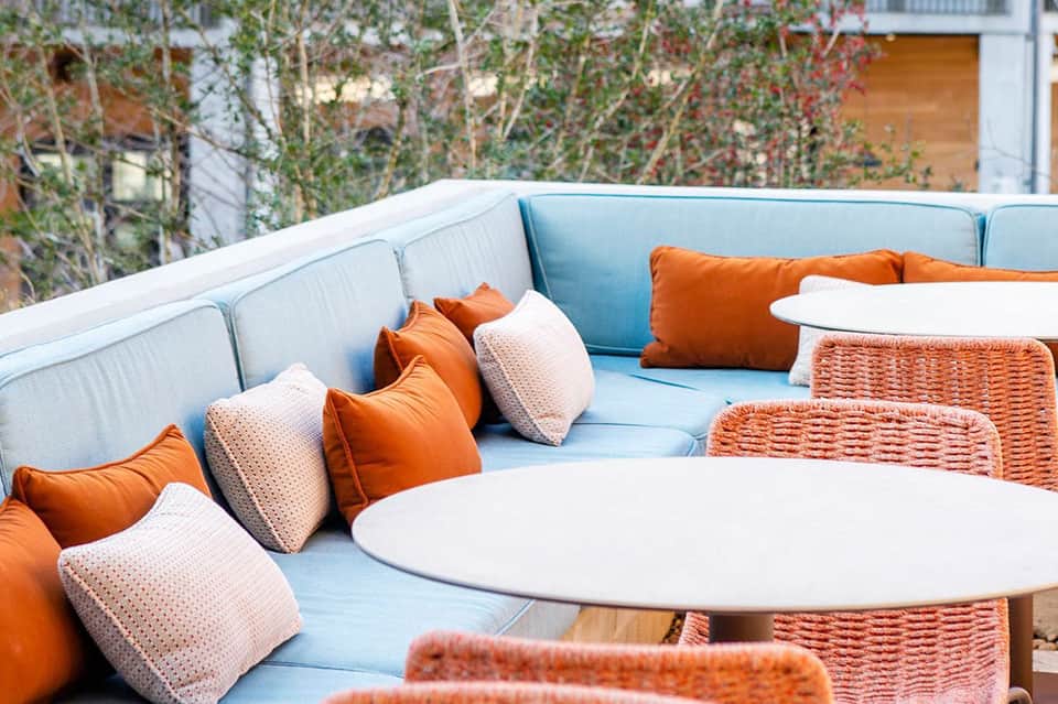 Outdoor lounge seating with light blue cushioned furniture and orange accent pillows
