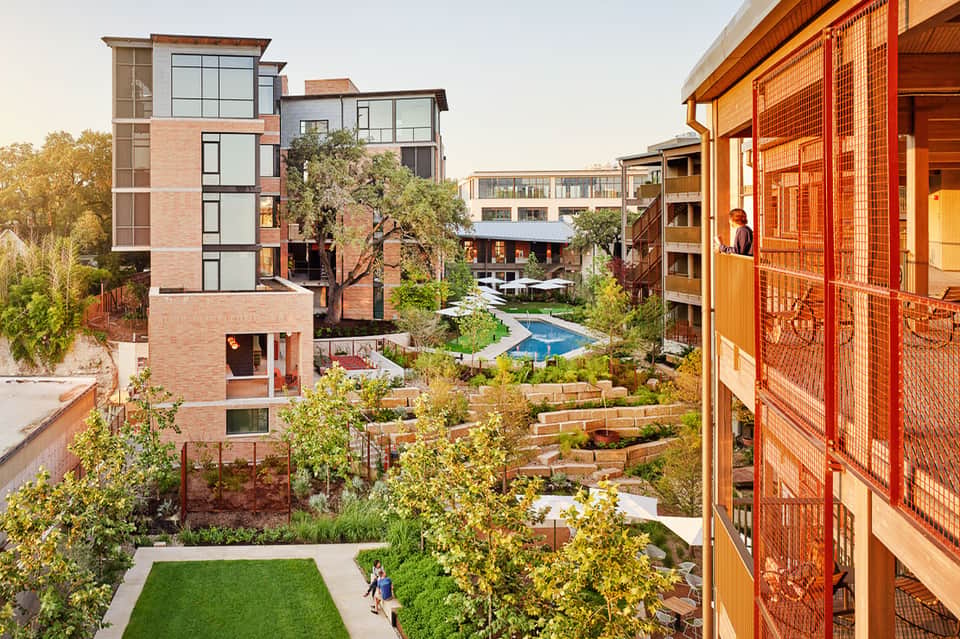 Modern residential courtyard with red brick buildings, small pool, landscaping, and walking paths