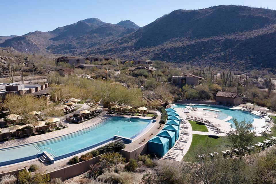 Resort pools nestled in desert mountains with cacti and adobe-style buildings