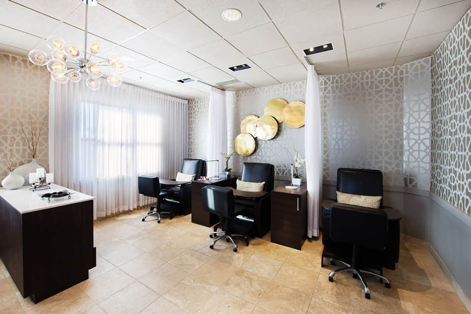 Professional office space with black desks, modern lighting, patterned wallpaper, and white curtains