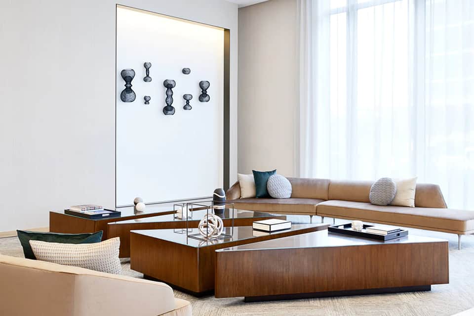 Modern hotel suite living area with tan sofa, wooden coffee table, and large abstract wall art