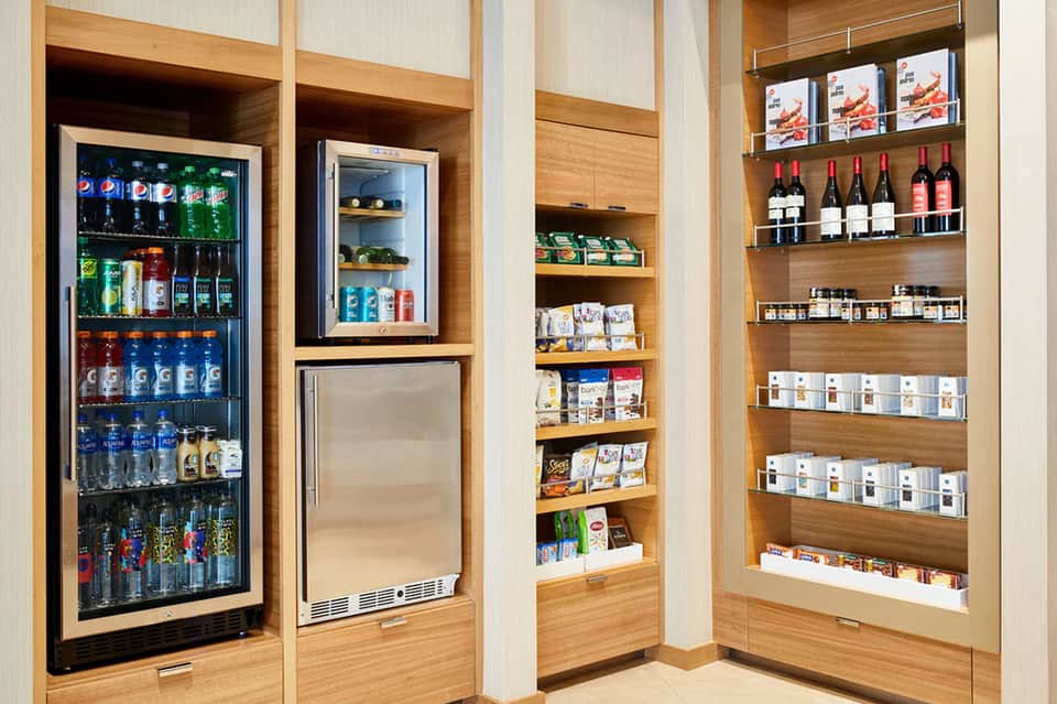 Resort minibar and beverage area with refrigerators, shelves of wine and snacks