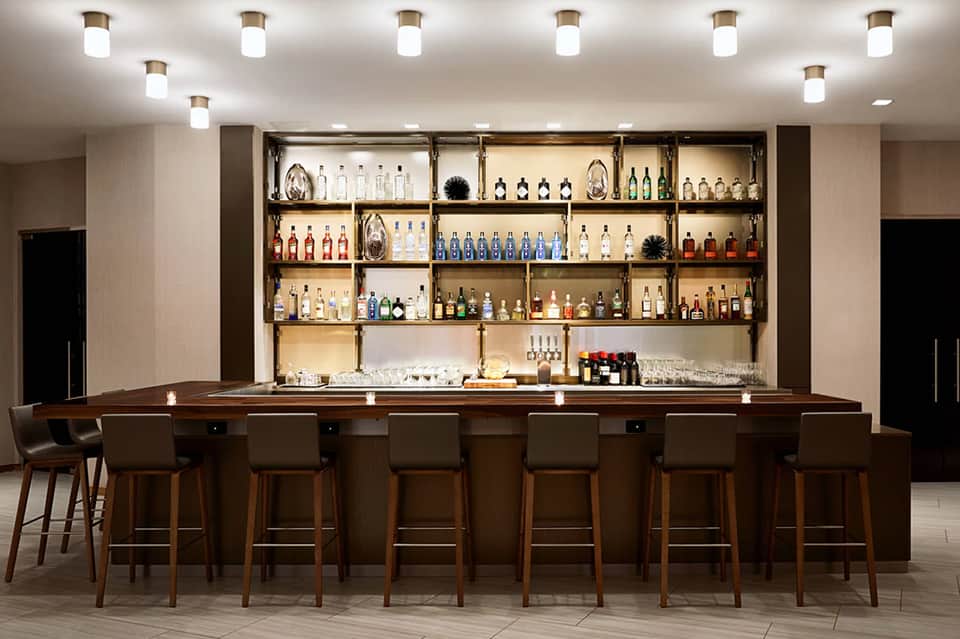 Full-service resort bar with extensive liquor collection on illuminated shelves