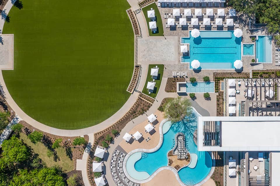 Aerial view of large resort with curved pool complex, lazy river, and manicured lawns