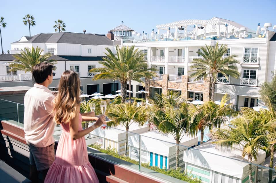 Couple viewing coastal resort buildings with palm trees and city skyline in distance