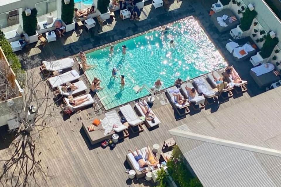 Aerial view of busy resort pool deck with sunbathers and surrounding loungers