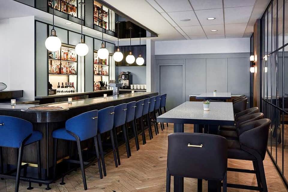 Contemporary bar and lounge with blue upholstered seating and shelved spirits display